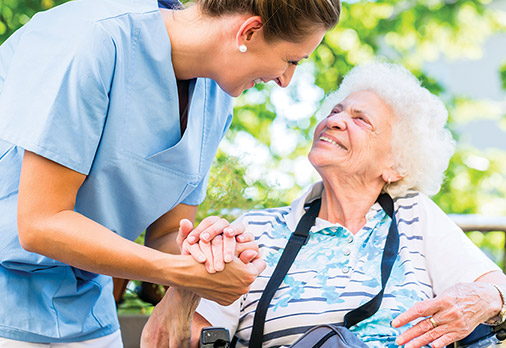 Long term caresupport nurse smiling at elderly woman patient in wheelchair
