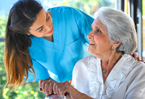 Skilled Memory support nurse leaning over and smiling at elderly woman patient