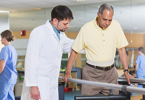 Rehab doctor helping elderly male patient during rehab
